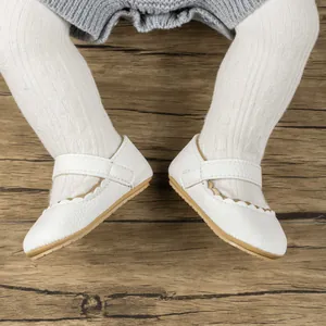Detail van witte Mary Jane baby loopschoenen met geschulpte randen en klittenband