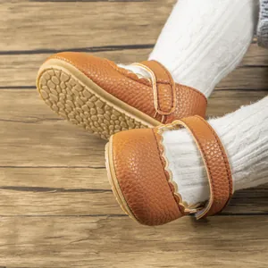 Detail van babyschoentjes met schulpranden, klittenband en antislip rubberen zolen