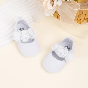 Primer plano de zapatos de bebé Mary Jane blancos con delicadas rosas de tela decorativas