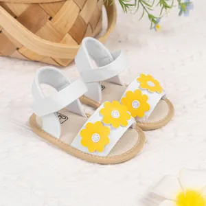 Détail de sandales d'été pour bébé en toile blanche avec fleurs jaunes et semelle souple