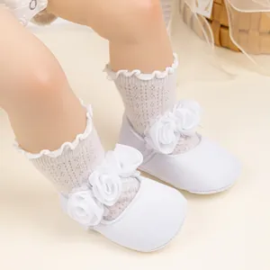 Primer plano de zapatos de bebé con flores de encaje y calcetines suaves de punto