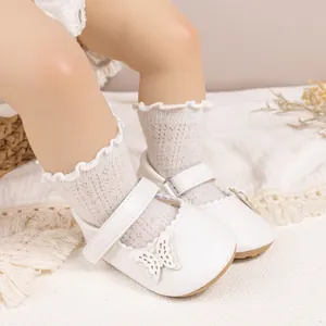 Gros plan de chaussures bébé Mary Jane blanches avec dentelle papillon et chaussettes