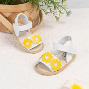 Gros plan de sandales blanches pour bébé avec marguerite jaune et bride velcro