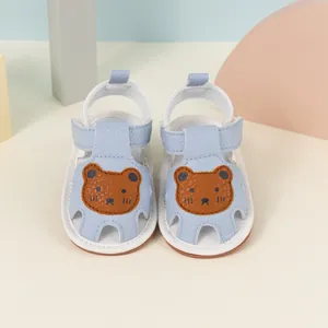 Detail of baby summer sandals featuring a brown bear motif and soft rubber sole in light blue