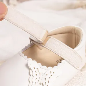 Détail du décor papillon et de la bride velcro sur les chaussures blanches bébé