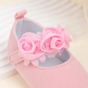 Primer plano de zapatos rosa para bebé con flores de satén 3D y textura de ante suave