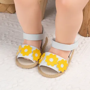 Gros plan de sandales blanches bébé avec fleur jaune et bride velcro ajustable