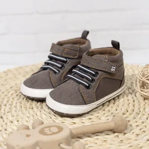 Detail of baby walking shoes with velcro strap and striped laces on a woven mat