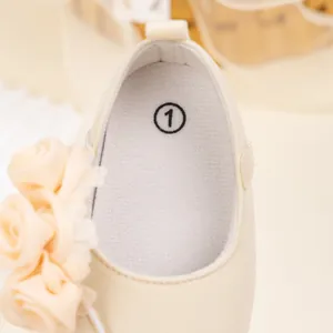 Detalle de zapatos de princesa para bebé con flor de encaje y suave textura crema