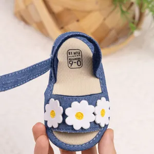 Détail macro de sandales pour bébé en denim bleu avec des décorations de marguerites