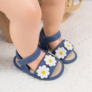 Détail des sandales bébé en jean bleu avec fleurs de marguerite et velcro