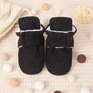 Gros plan de chaussures bébé en velours noir avec doublure polaire et décorations