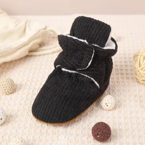 Détail de bottines bébé en velours noir avec doublure en fourrure et fermeture velcro