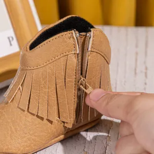 Détail de la fermeture éclair latérale et des franges marron sur ces bottes bébé