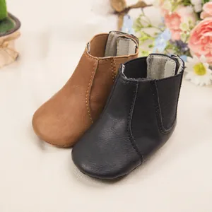 Detalle de botas Chelsea para bebé en cuero sintético marrón y negro con elástico