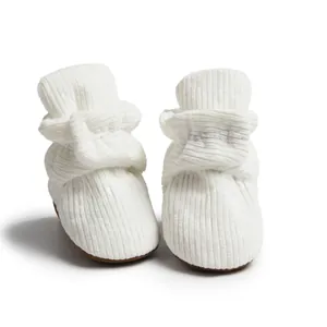 Détail de la texture velours blanc et semelle souple des chaussures thermiques bébé