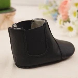 Detalle de botines Chelsea negros para bebé con paneles elásticos y textura de cuero suave