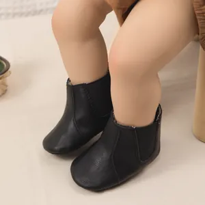 Detalle de botines Chelsea de cuero negro para bebé con bandas laterales elásticas