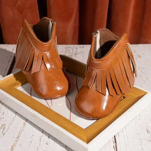 Braune Fransen-Babystiefel aus PU-Leder, präsentiert auf einem Vintage-Holzrahmen