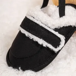 Close-up of baby winter shoes with soft black fabric and white faux fur lining details