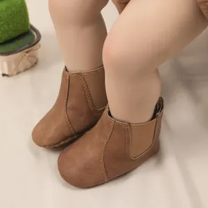 Detalle de botas de cuero marrón oscuro para bebé con paneles elásticos laterales