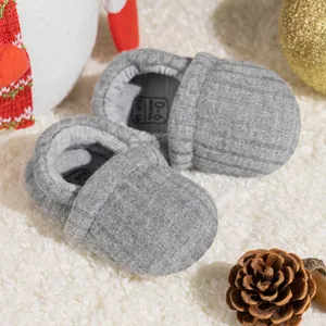 Detail of grey knitted baby shoes showing 0-6 months size marking on warm fleece