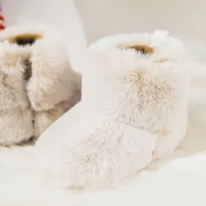 Close-up of soft fluffy cream faux fur baby winter boots with warm plush texture