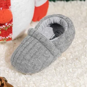 Close-up of grey knit baby walker shoe with size 18 on soft plush background