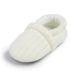Close-up of white knitted baby shoes showing ribbed texture and elastic ankle cuffs
