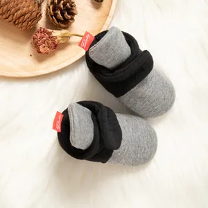 Details von gestrickten Baby-Socken-Schuhen in Grau und Schwarz mit weicher Sohle