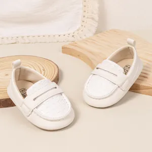 Detail of white PU leather baby loafers with woven texture and heel pull tabs