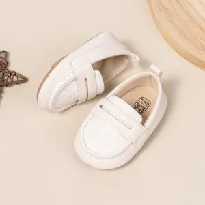 Close-up of white woven baby loafers with soft sole and 0-6 months size marking