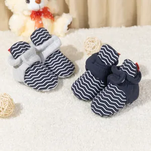 Makro-Detail von Baby-Lauflernschuhen mit blauem Wellenmuster auf weichem Teppich