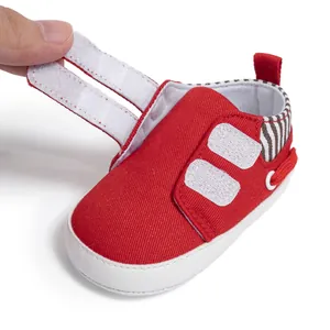 Détail de chaussure bébé en toile rouge avec double fermeture velcro et semelle souple blanche