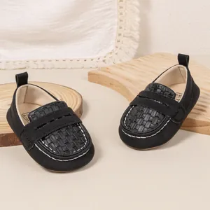 Close-up of black infant loafers featuring woven texture and white contrast stitching