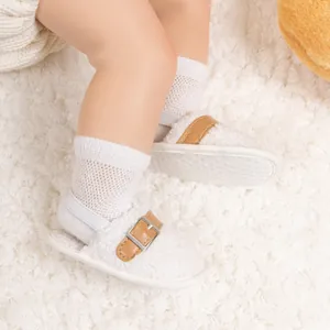 Detailed close-up of warm baby plush shoes with non-slip dots on white fleece rug