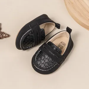 Detail shot of black soft-sole baby shoes with white stitching and woven toe accents