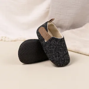 Detail of baby walking shoes with non-slip rubber soles and breathable tweed fabric texture
