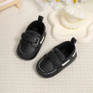 Detail view of black lychee texture baby shoes with white stitching and velcro strap