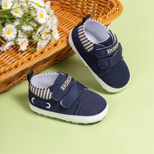 Détail de chaussures bébé en toile bleu marine avec velcro et texte doré FASHION