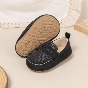 Macro detail of infant loafers featuring textured black fabric and non-slip soft soles