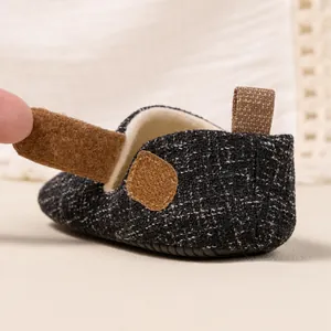 Detail showing the adjustable brown Velcro strap on a tweed baby walking shoe