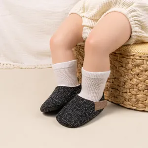 Close-up of baby walking shoes in black and grey tweed fabric with textured weave