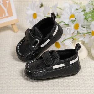 Detailed top view of black faux leather baby moccasins with white stitching and velcro
