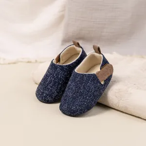 Detail of baby walking shoes with dark blue woven fabric and adjustable straps