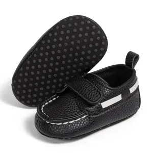 Detail of black infant moccasins with white stitching and non-slip dotted sole