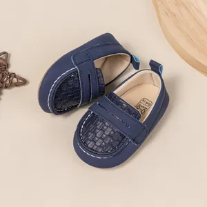 Detail view of navy blue soft-sole baby loafers with leather texture and pull tab