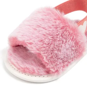 Detail of pink faux fur baby slippers featuring elastic heel strap with white hearts