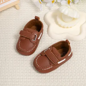 Close-up of brown faux leather baby shoes with velcro strap and white stitching detail