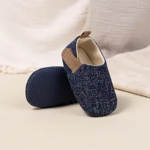 Detail showing blue tweed fabric texture and brown leather accents on baby walking shoes